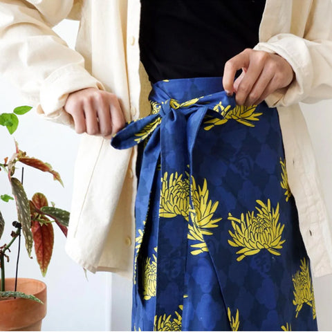 A woman is wearing a high-waisted wrap midi skirt with a chrysanthemum blossom pattern.
