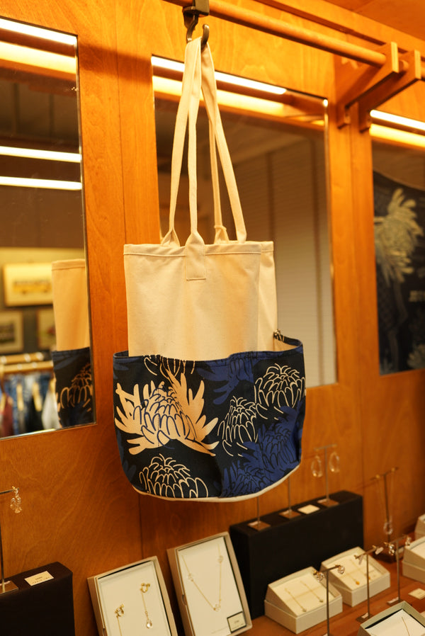 GOC Studio chrysanthemum canvas tool tote hanging in store, showing the printed lower panel and canvas body