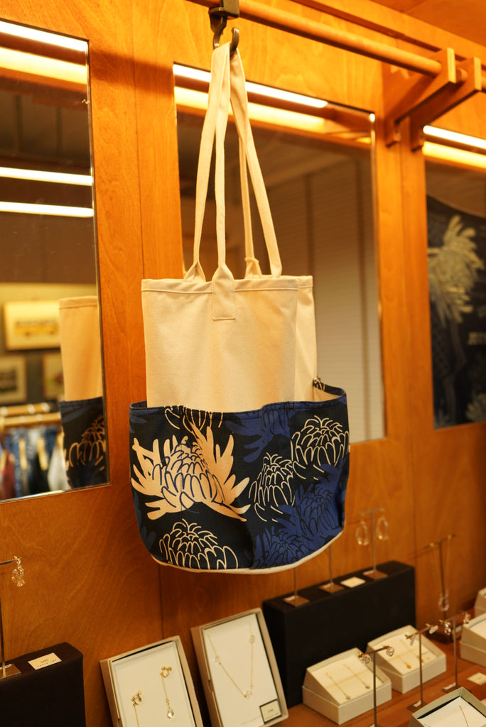 GOC Studio chrysanthemum canvas tool tote hanging in store, showing the printed lower panel and canvas body