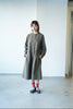  a long-sleeved, knee-length olive green utility dress with brown buttons, paired with red socks and navy sneakers.