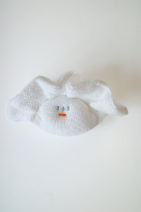 A white textured fabric hair claw clip shaped like a small bunny face, featuring embroidered blue eyes and a tiny orange nose, shown on a plain white background.