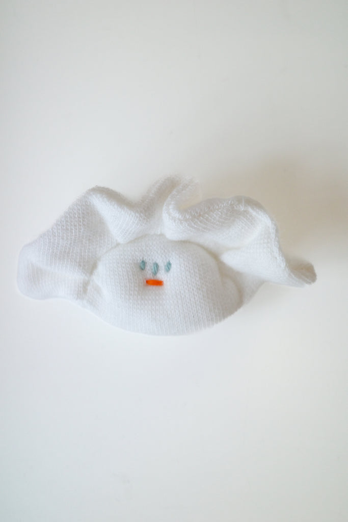 A white textured fabric hair claw clip shaped like a small bunny face, featuring embroidered blue eyes and a tiny orange nose, shown on a plain white background.