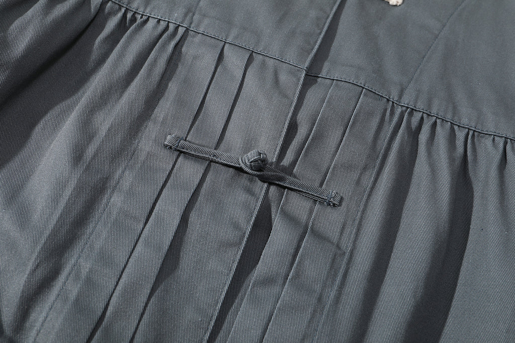 close up of front pleat detail and tonal traditional knot button on a Hong Kong made GOC Studio steel blue Japanese cotton twill oriental jacket